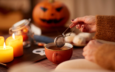 Image showing woman's hand with tea infuser and mug on halloween