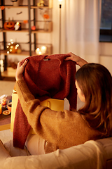 Image showing woman taking cardigan from shopping bag at home