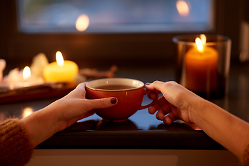 Image showing hands with cup of tea on window sill in autumn