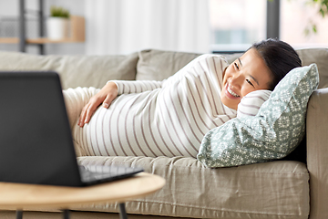 Image showing happy pregnant asian woman with laptop at home