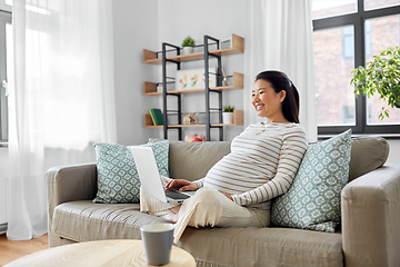 Image showing happy pregnant asian woman with laptop at home