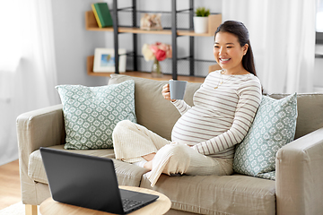 Image showing happy pregnant asian woman with laptop at home