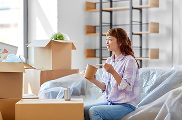 Image showing happy woman moving to new home and eating wok