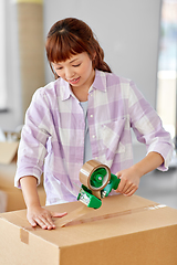 Image showing woman with adhesive tape packing box at new home