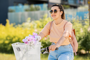 Image showing happy woman with earphones riding bicycle in city