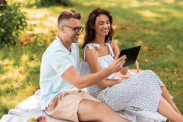 Image showing happy couple with tablet pc at picnic in park