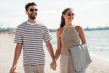 Image showing happy couple with blanket walking along beach