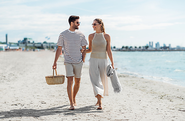 Image showing happy couple with picnic basket walking on beach