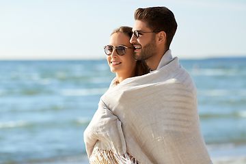 Image showing happy couple covered with blanket hugging on beach