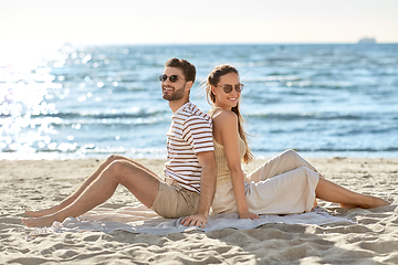 Image showing happy couple sitting back to back on summer beach