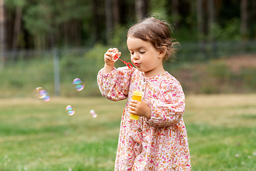 Image showing happy baby girl blowing soap bubbles in summer