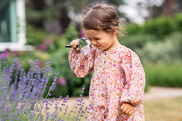 Image showing baby girl with magnifier looking at garden flowers