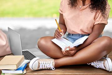 Image showing african american student girl making notes in book