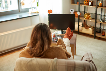 Image showing young woman watching tv at home on halloween