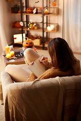 Image showing woman writing to diary at home on halloween