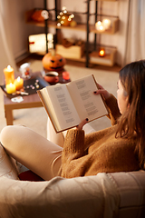 Image showing young woman reading book at home on halloween