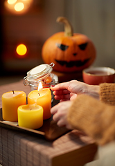 Image showing hand with match lighting candle on halloween