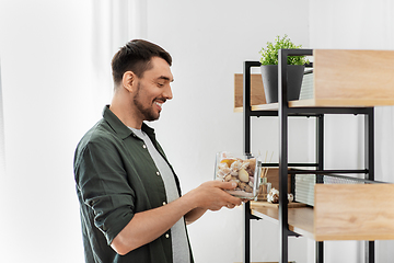 Image showing man decorating home with seashells in vase