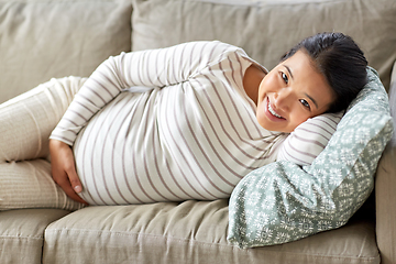 Image showing happy pregnant asian woman lying on sofa at home