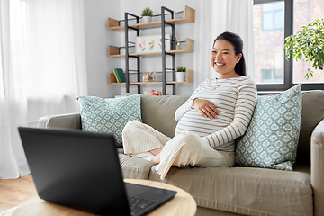 Image showing happy pregnant asian woman with laptop at home