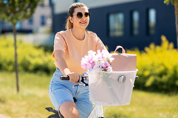 Image showing woman with flowers in bicycle basket in city