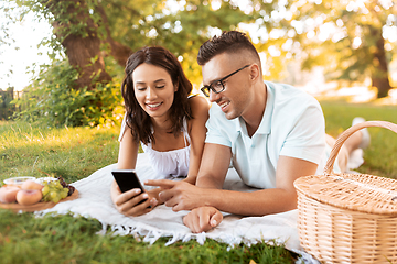 Image showing happy couple with smartphone at picnic in park