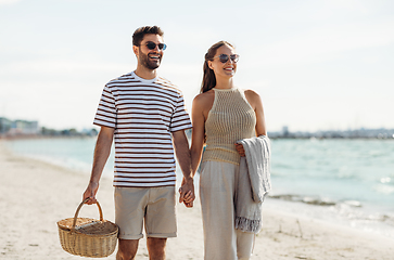 Image showing happy couple with picnic basket walking on beach