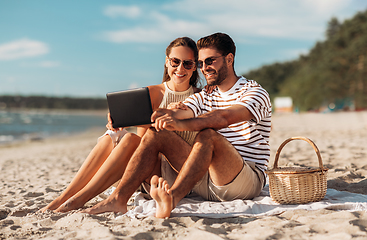 Image showing happy couple with tablet pc at picnic on beach