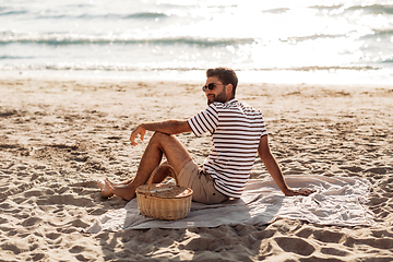 Image showing man with picnic basket on blanket on summer beach