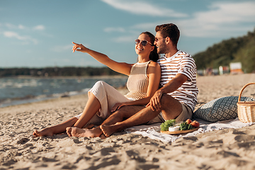 Image showing happy couple with food having picnic on beach