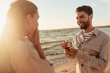 Image showing man with ring making proposal to woman on beach