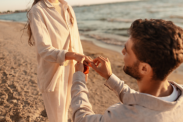 Image showing man with ring making proposal to woman on beach