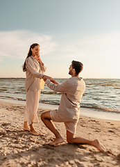 Image showing man with ring making proposal to woman on beach