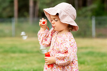 Image showing happy baby girl blowing soap bubbles in summer