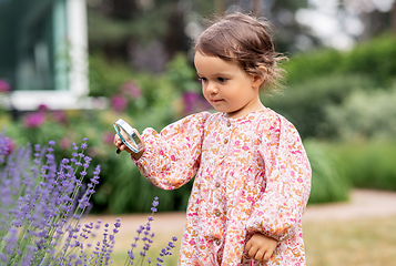 Image showing baby girl with magnifier looking at garden flowers