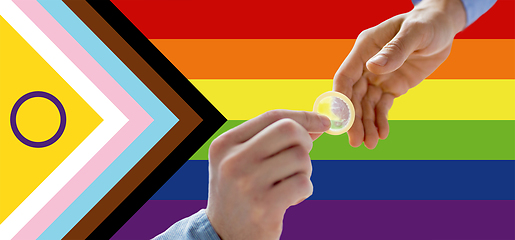 Image showing close up of male gay couple hands giving condom