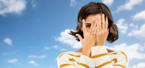 Image showing young woman looking by one eye through her fingers