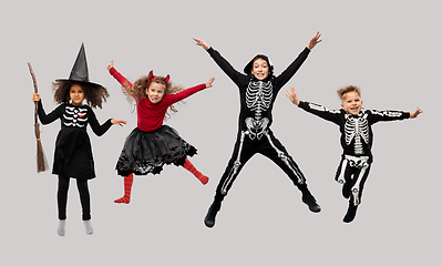 Image showing happy children in halloween costumes jumping