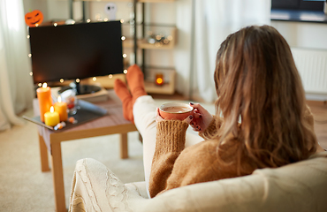 Image showing woman watches tv and drinks cocoa on halloween