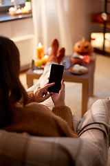 Image showing woman using smartphone at home on halloween