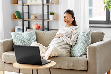 Image showing happy pregnant asian woman with laptop at home