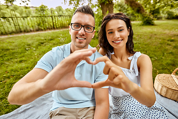 Image showing happy couple making finger heart at summer park