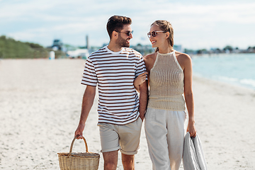 Image showing happy couple with picnic basket walking on beach