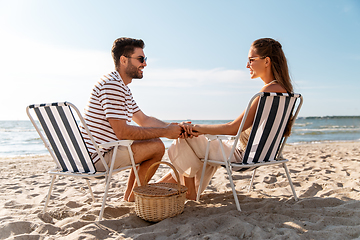 Image showing happy couple sitting in folding chairs on beach