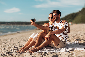 Image showing happy couple taking selfie by smartphone on beach