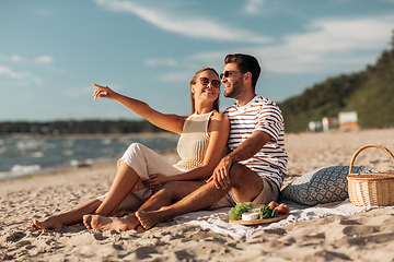 Image showing happy couple with food having picnic on beach