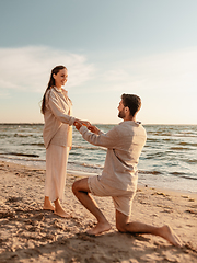 Image showing man with ring making proposal to woman on beach