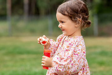 Image showing happy baby girl with soap bubble blower in summer