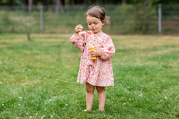 Image showing happy baby girl blowing soap bubbles in summer