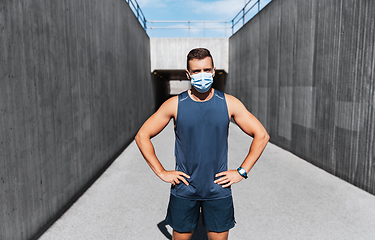 Image showing young man in medical mask doing sports outdoors